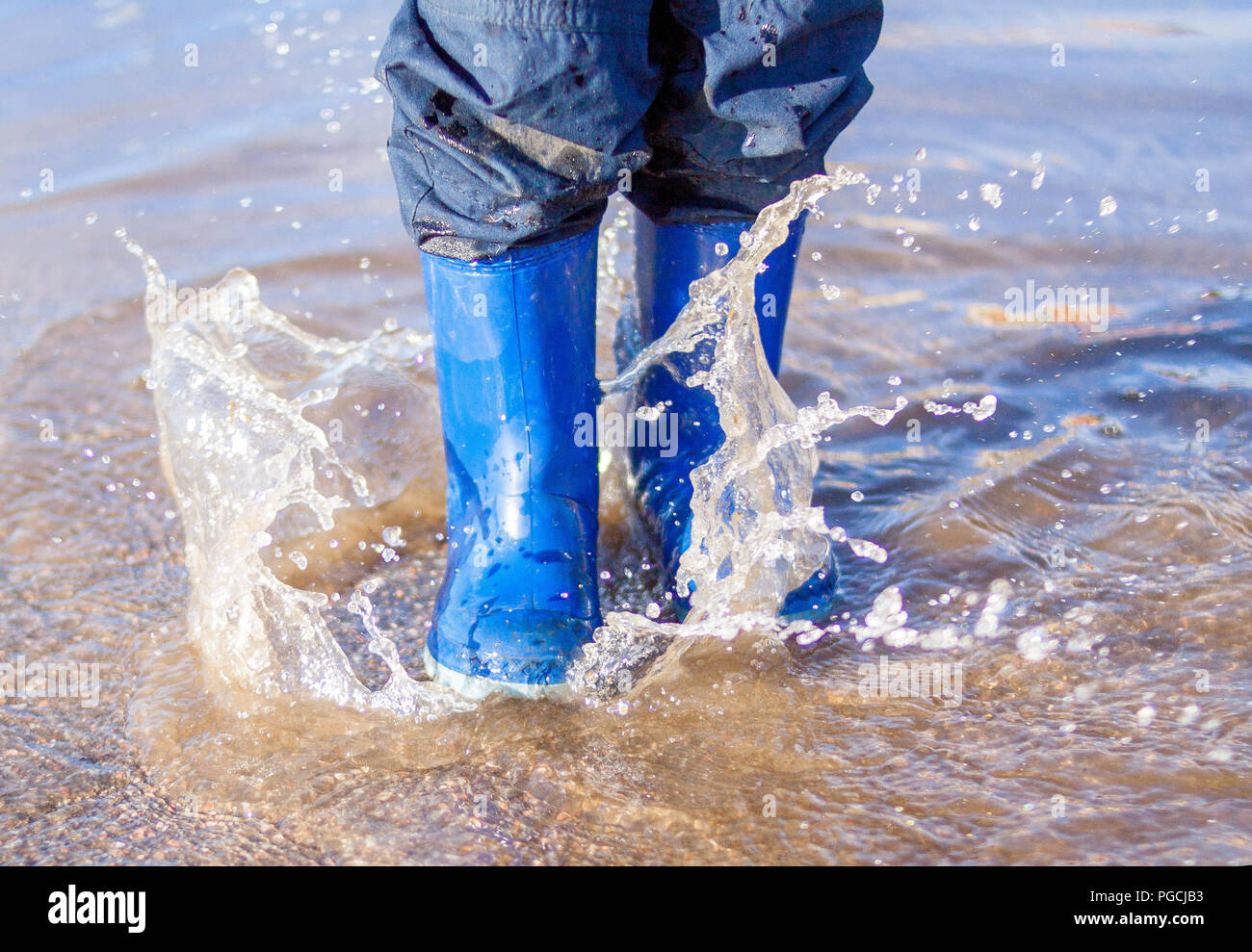 L'action de Gel jambes enfant bottes en caoutchouc bleu en sautant  par-dessus une flaque d'eau après la pluie au printemps, les gouttelettes  d'eau Photo Stock - Alamy