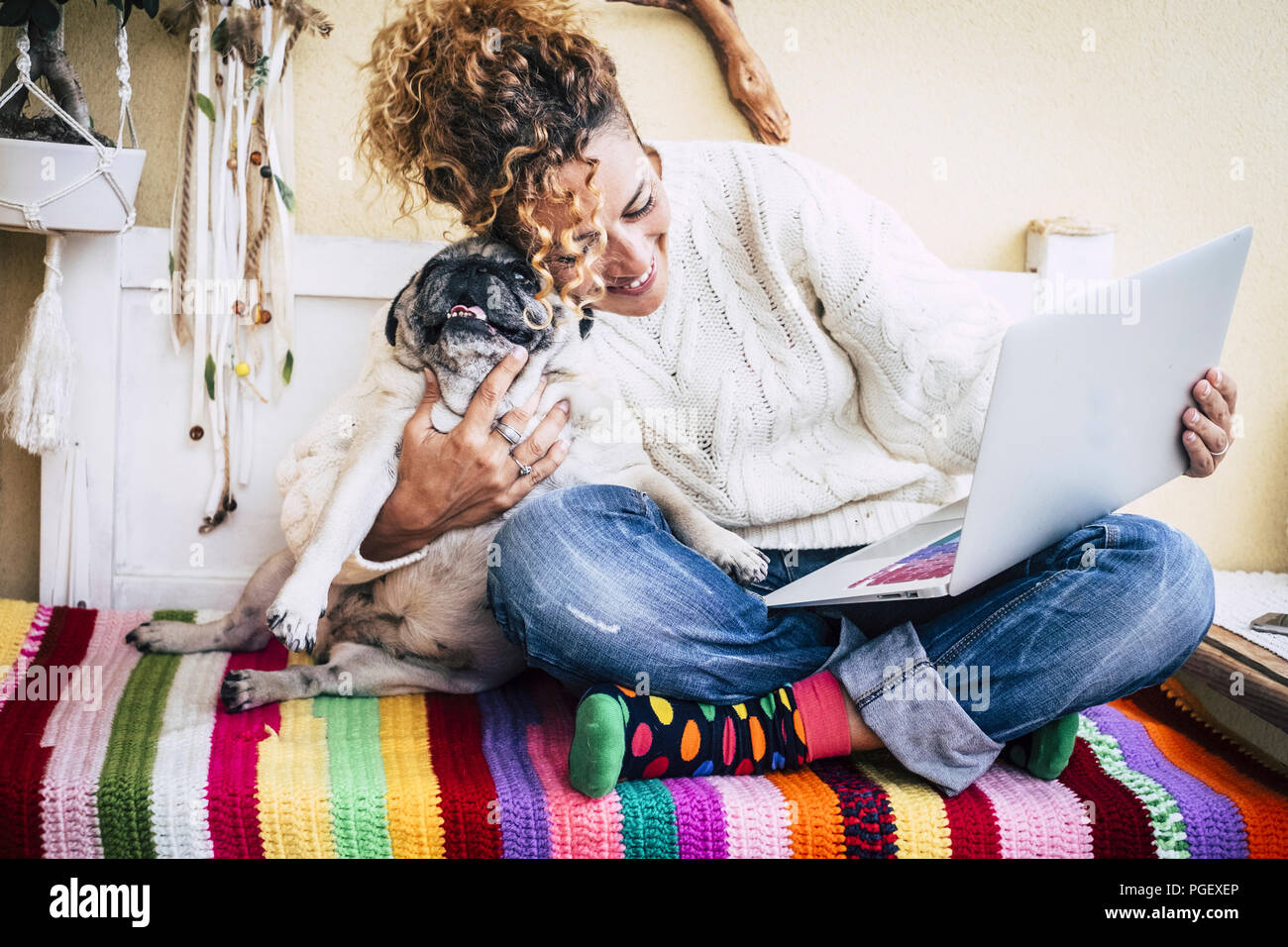 Du vrai meilleur amis cheerful woman working at laptop sur la terrasse à la maison tout en accolade de son mieux l'amour et friends smiling pug chien assis à sa gauche. Banque D'Images