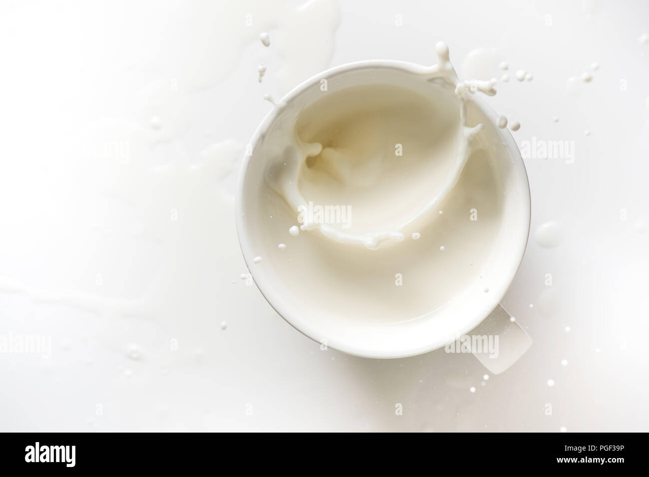 Vue de dessus de splash de lait en verre sur fond blanc Banque D'Images
