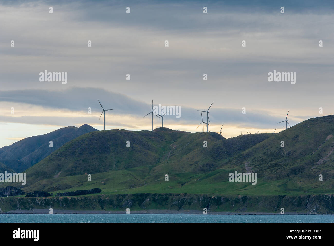 Les éoliennes sont hauts placés sur une colline au Cap Terewhiti, Nouvelle-Zélande. Paysage pittoresque, le vert des collines, le lever du soleil ciel coloré Banque D'Images