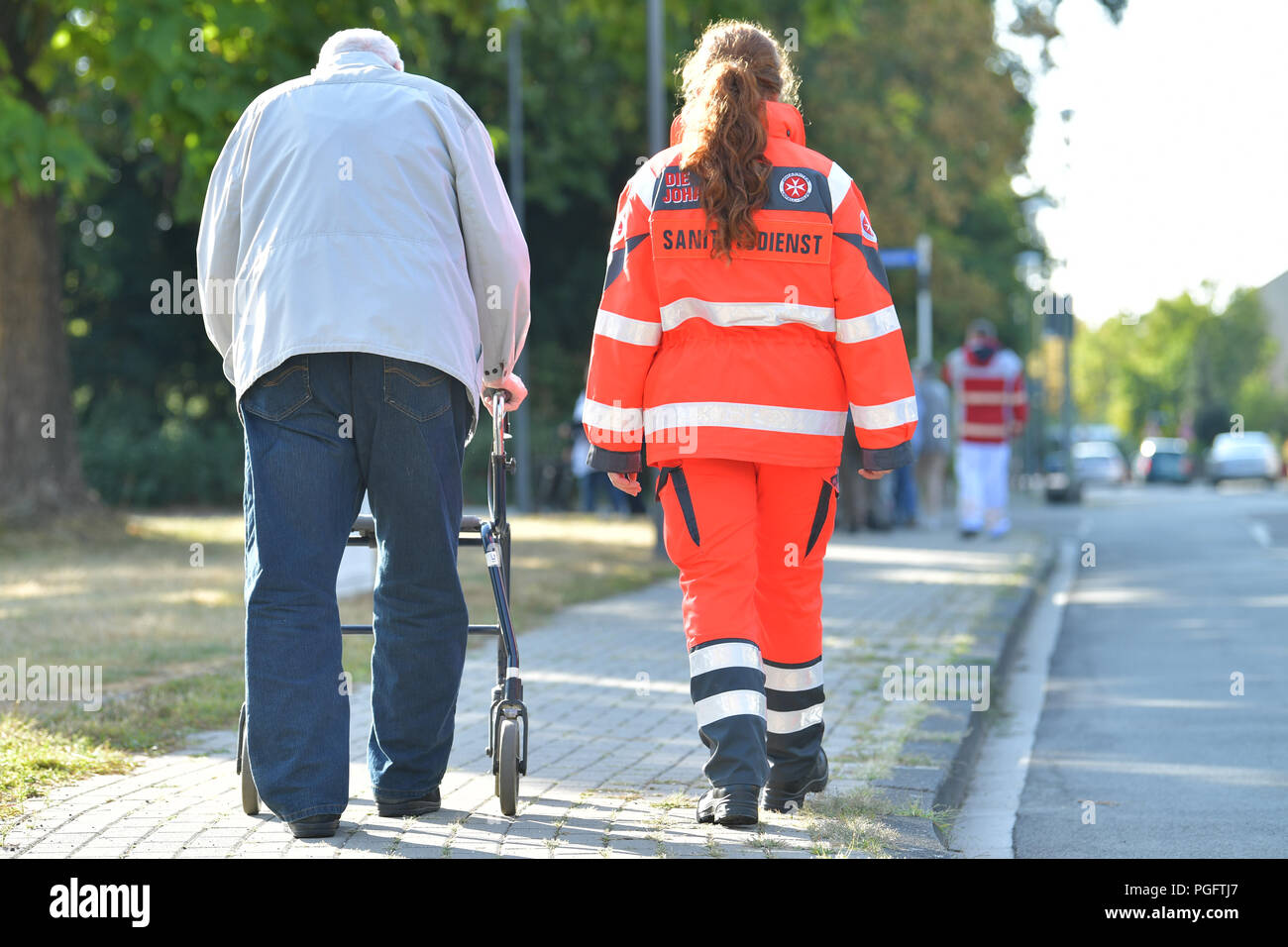 Ludwigshafen, Allemagne. Août 26, 2018. Un résident de la maison de soins infirmiers municipales 'Haus Friesenheim' est accompagné d'un paramédic en quittant l'établissement de soins infirmiers. Autour de 18 500 personnes ont dû être évacués pour la defusal d'un 500-kilogramme bombe aérienne de la Seconde Guerre mondiale. Credit : Uwe Anspach/dpa/Alamy Live News Banque D'Images