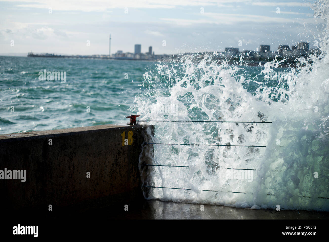 Brighton Marina vagues fracassant contre mur avec Brighton Pier et j360 à l'arrière-plan. Banque D'Images