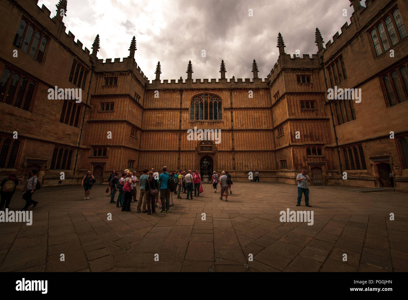 L'ancienne Bibliothèque Bodléienne avec un moody sky dans l'arrière-plan et les touristes au premier plan explorer le siège de l'apprentissage à l'Université d'Oxford Banque D'Images