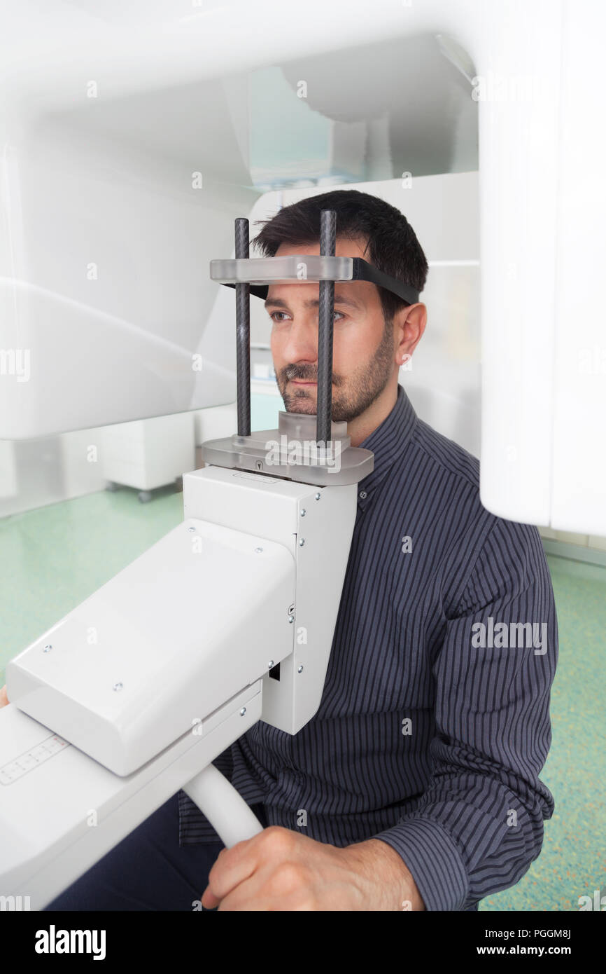 Portrait jeune homme ayant une vue panoramique sur la radiographie numérique de ses dents dans le cabinet dentaire. Banque D'Images