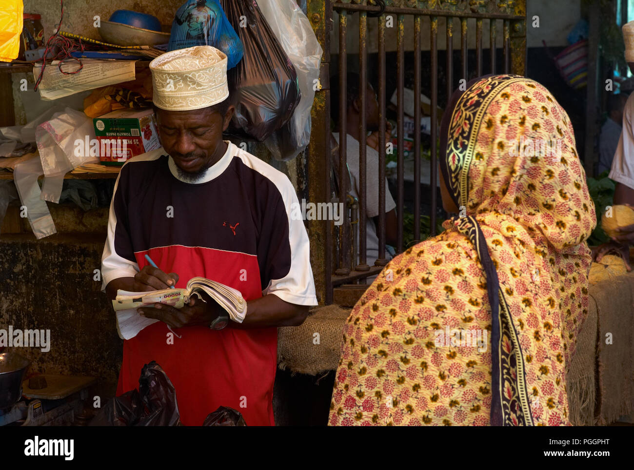 STONE Town, Zanzibar, Tanzanie - 06 juillet 2008 : Forfaits de prendre une note. Une transaction entre un homme et une femme dans un marché à Stone Town, Zanzibar. Banque D'Images