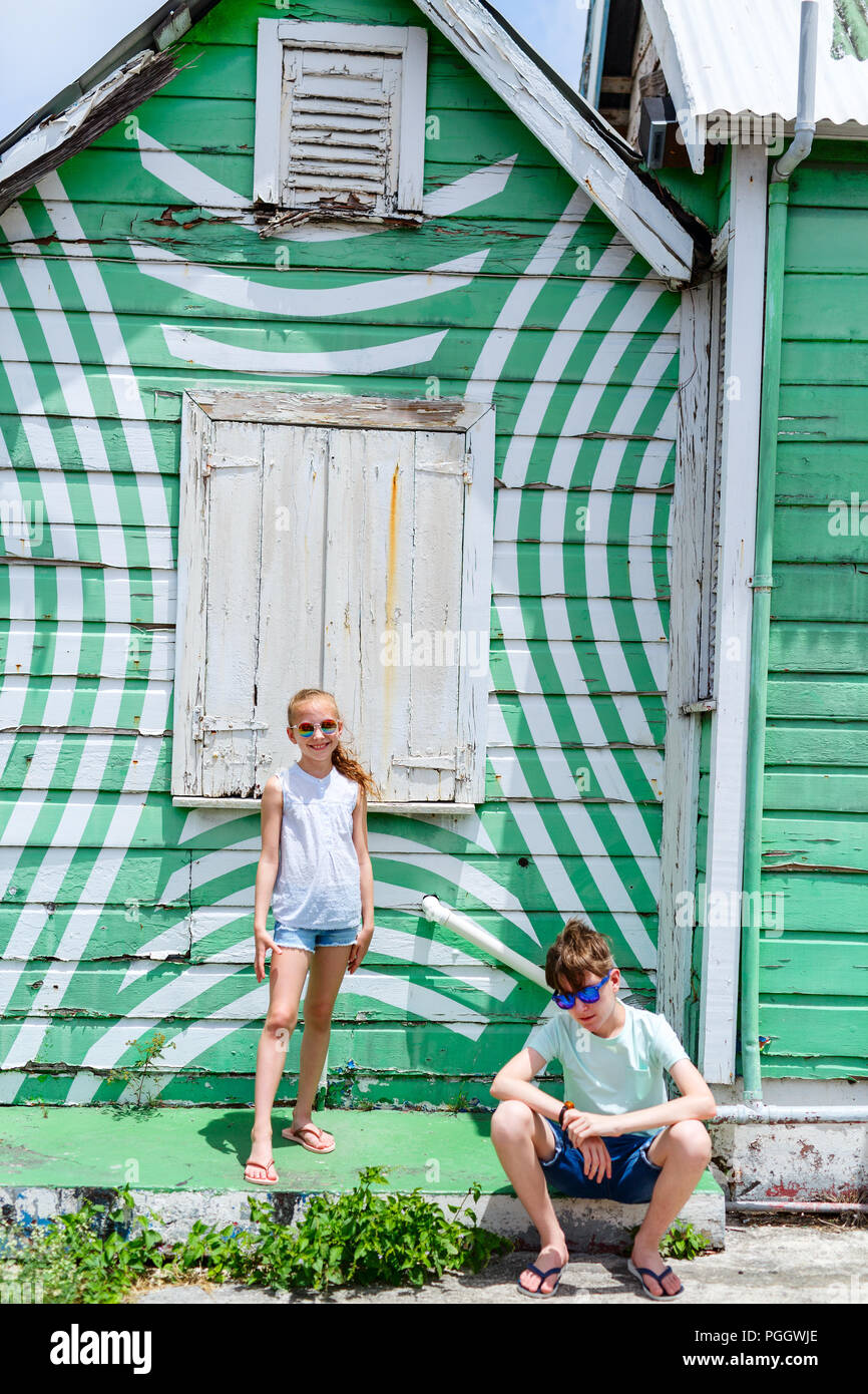 Deux enfants garçon et fille à l'extérieur contre maison colorée sur l'île de la Barbade dans les Caraïbes Banque D'Images