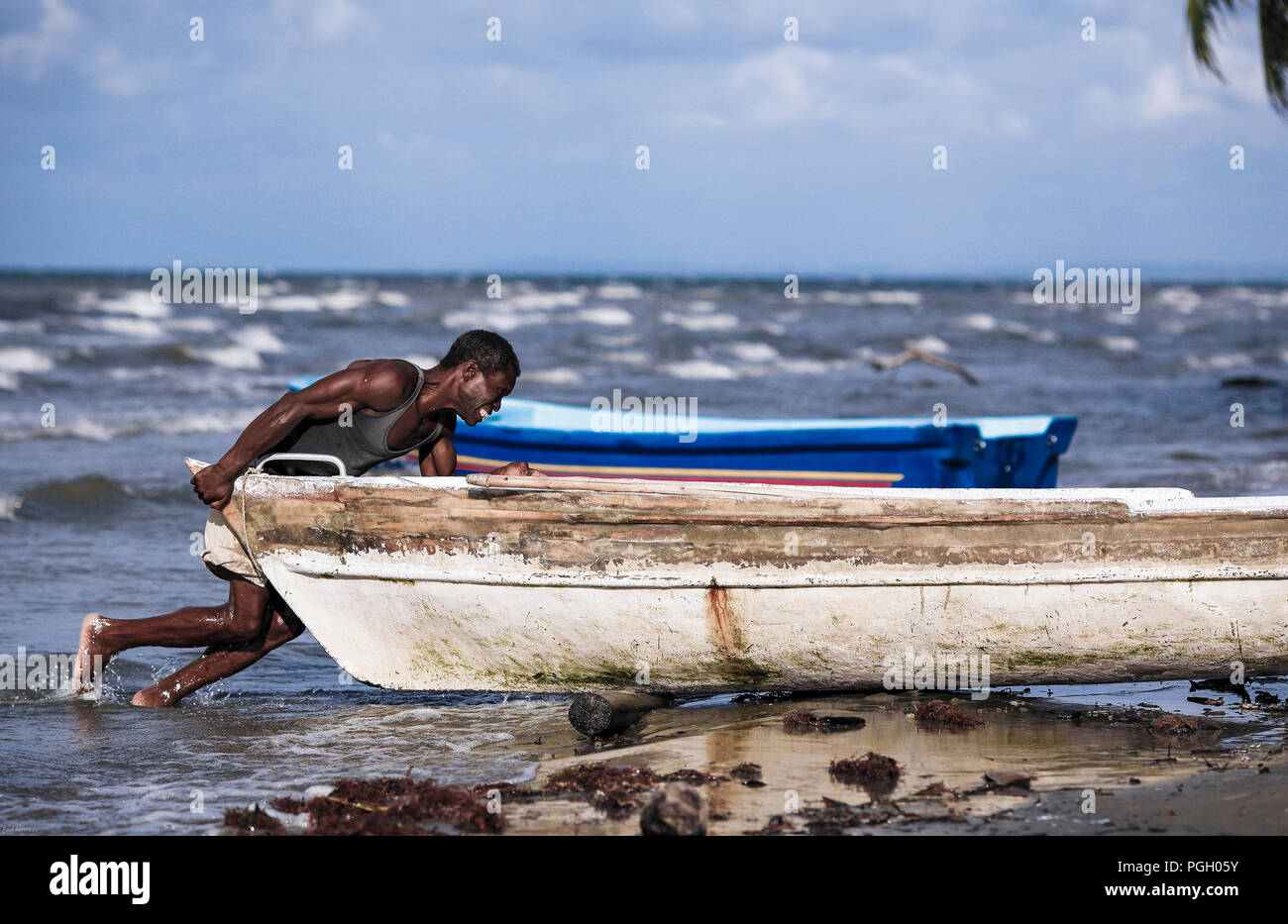 Fisherman poussant son bateau de l'océan dans Livinston, Guatemala Banque D'Images