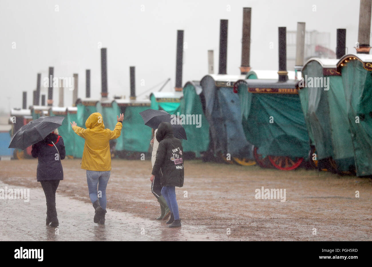 Les visiteurs font leur chemin passé couvert comme moteurs de traction à vapeur d'une douche à effet pluie passe au-dessus de la Grande Vapeur Dorset, juste à Blandford, Dorset, où des centaines de moteurs de traction à vapeur période lourde et l'équipement mécanique de toutes les époques se sont réunis pour la foire annuelle pour célébrer le 50e anniversaire de l'émission. Banque D'Images