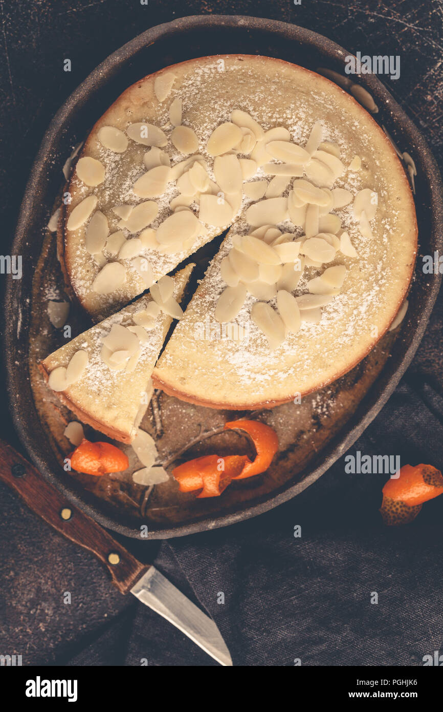 Gâteau aux amandes sur plat noir, vue du dessus, un arrière-plan sombre. Tarte aux noix avec orange. Banque D'Images