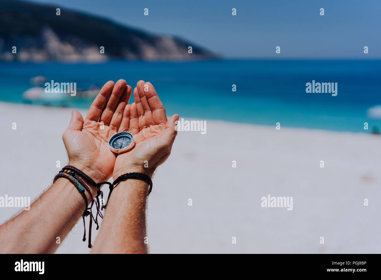 Main ouverte paume holding metal boussole contre sable et mer bleue. Vous cherchez votre chemin concept. Pov point de vue Banque D'Images