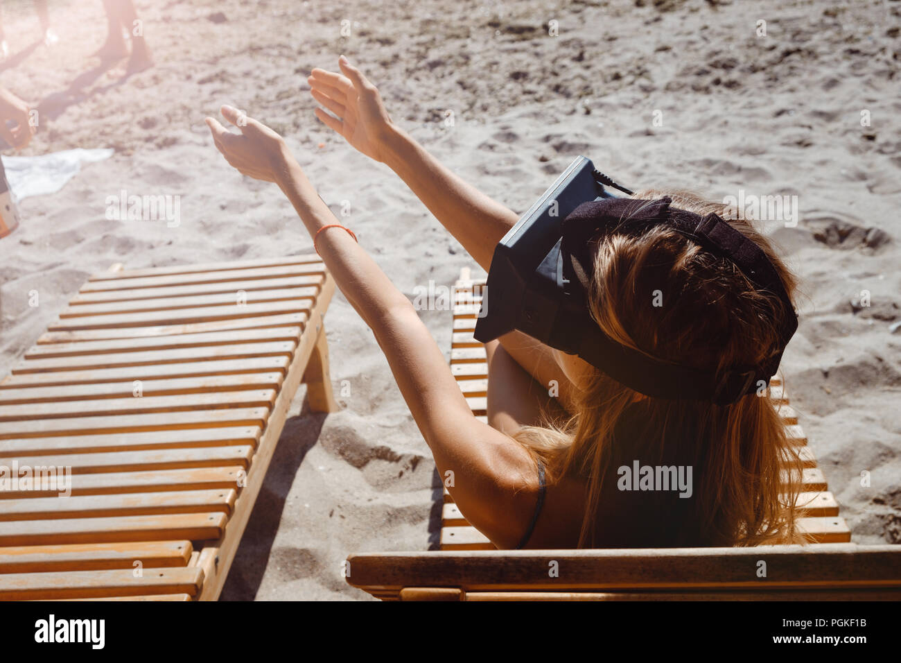 Young woman reaching out en lunettes VR on beach Banque D'Images