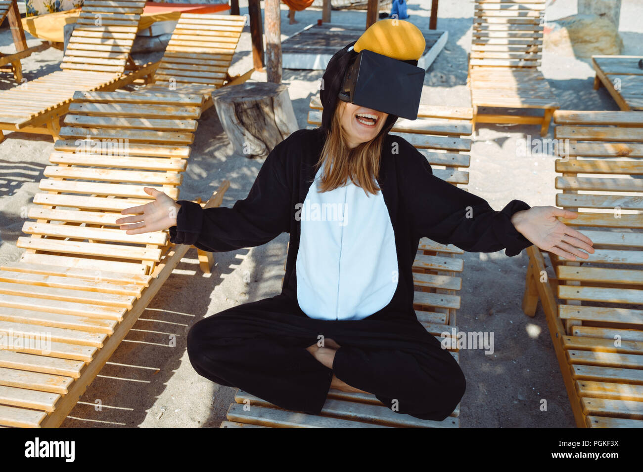 Jeune femme fou en costume de pingouin en méditant sur la plage. Banque D'Images
