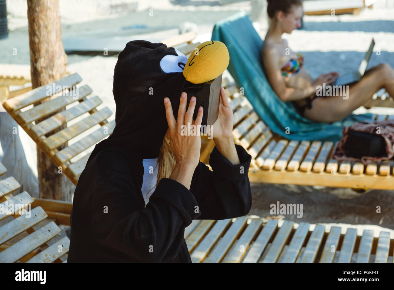 Jeune femme fou en costume de pingouin en méditant sur la plage. Banque D'Images