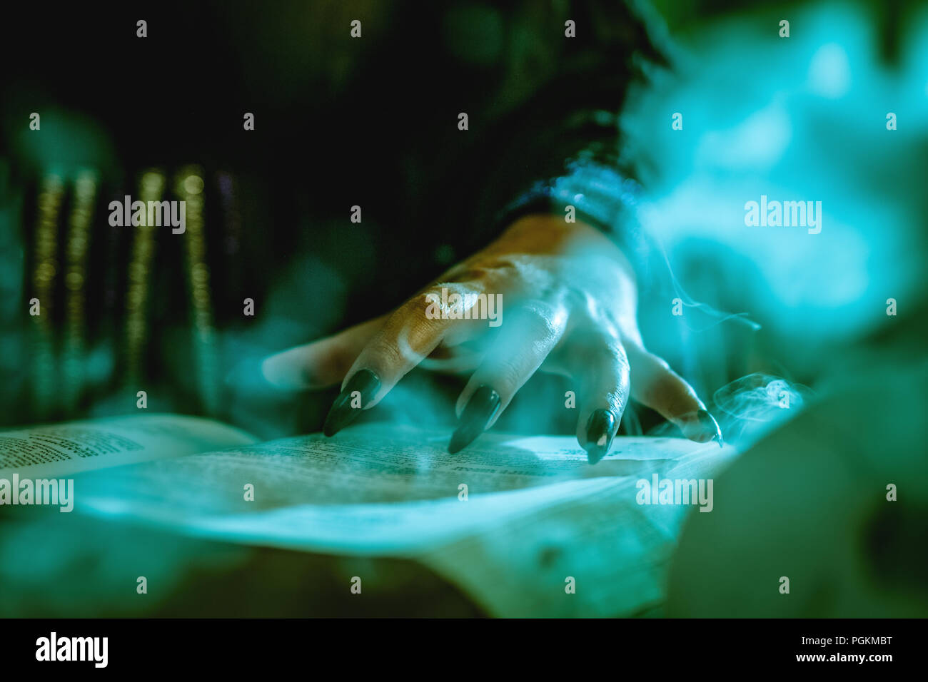 Close-up of a witch's part avec des clous noir fumé sur livre de recette magique et avec une baguette magique. Banque D'Images