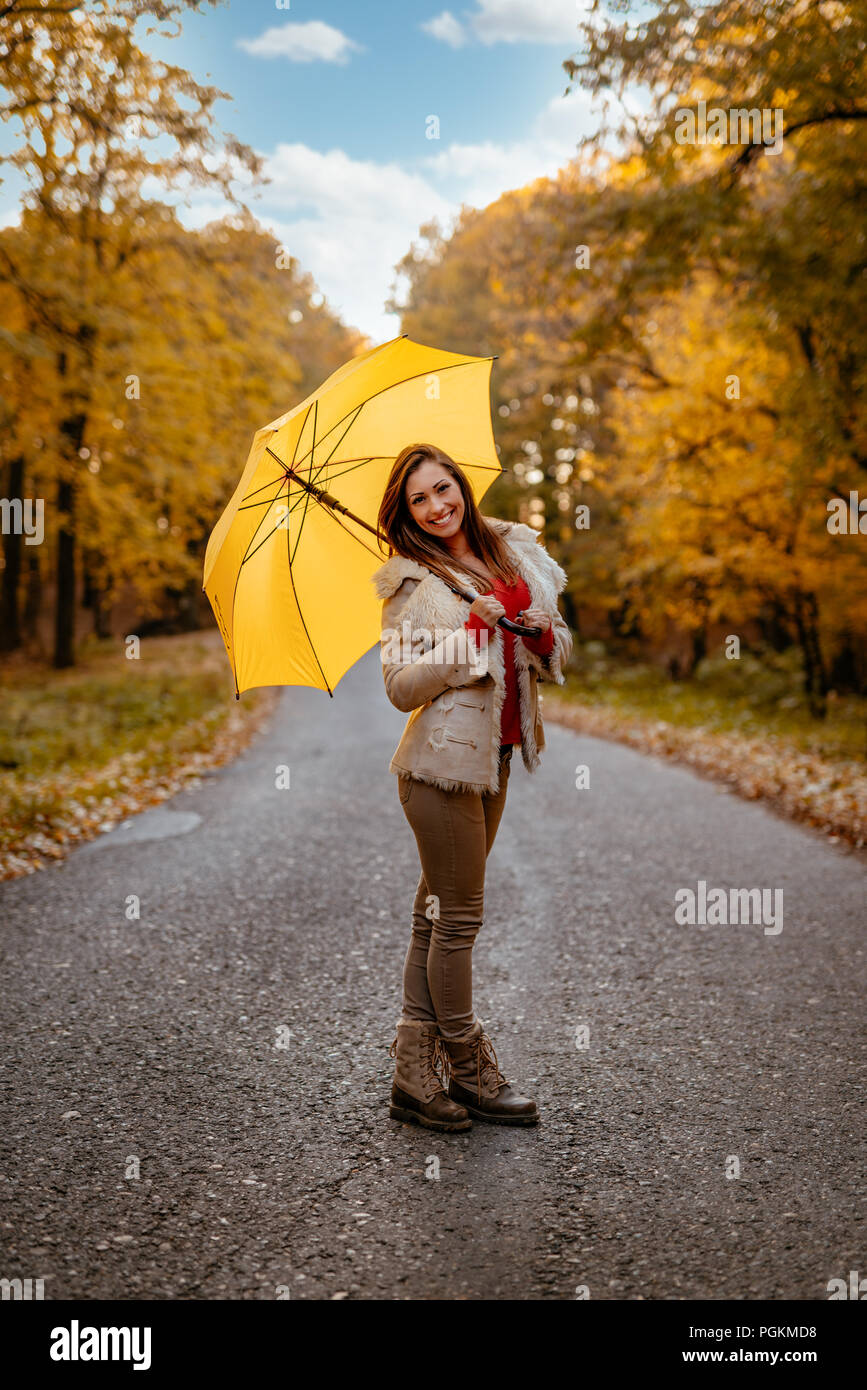Joyeux belle jeune femme avec parapluie jaune ayant in sunny park en couleurs de l'automne. Banque D'Images