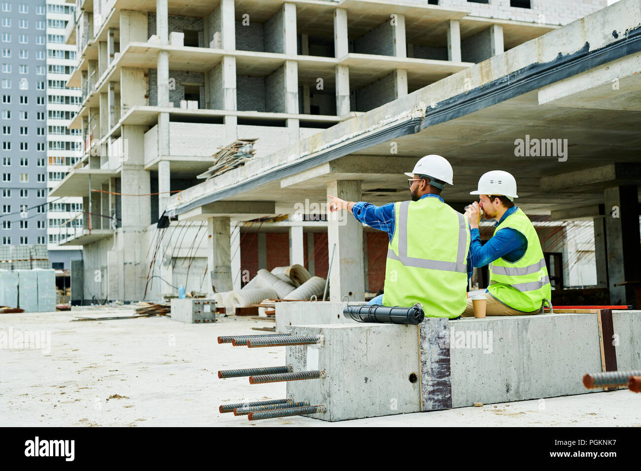 Retour Voir portrait de deux travailleurs portant des casques de communication tout en profitant d'pause café on construction site Banque D'Images