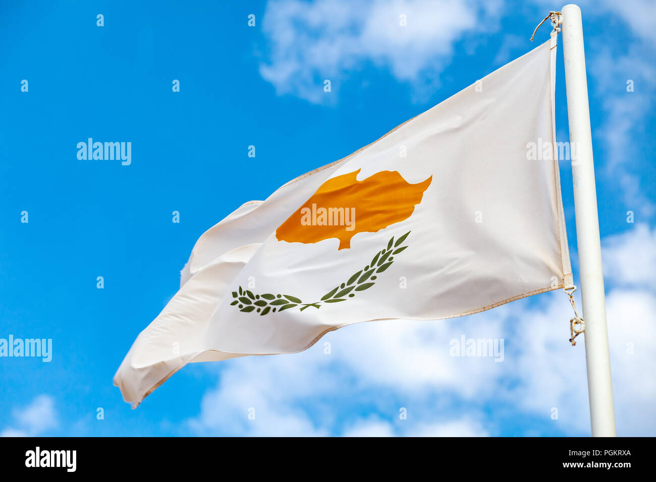 Brandissant le drapeau national de Chypre sur le vent sur fond de ciel bleu Banque D'Images
