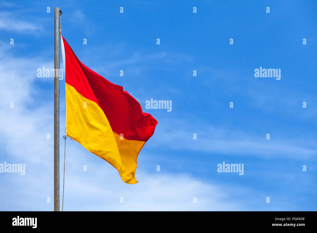 Drapeau rouge et jaune sur une plage sur fond de ciel bleu Banque D'Images Drapeau rouge et jaune sur une plage sur fond de ciel bleu Banque D'Images