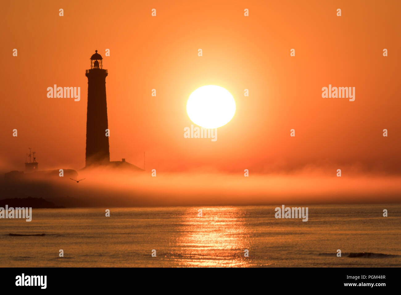 Lever du Soleil par le phare sur un matin brumeux Banque D'Images