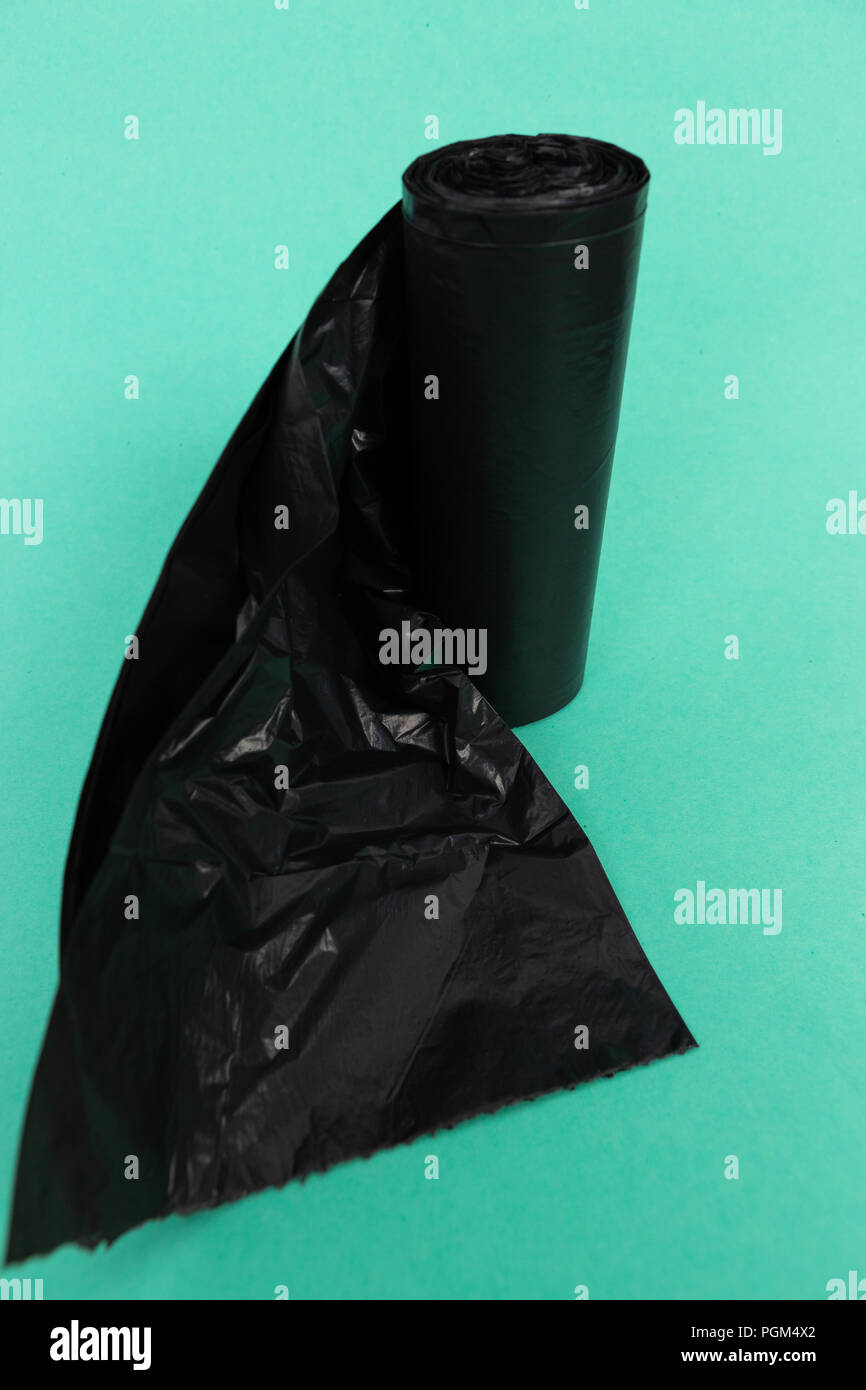Les noirs en plastique à usage unique sac d'ordure ordures comme rouleau de nettoyage de ménage à usage unique concept de l'objet isolé sur backgruond vert Banque D'Images