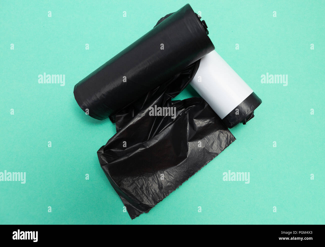 Déchets en plastique noir sac poubelle poubelle poubelle rouleaux inutilisés comme simple outil de recyclage des déchets de ménage pollution concept isolé sur fond vert Banque D'Images
