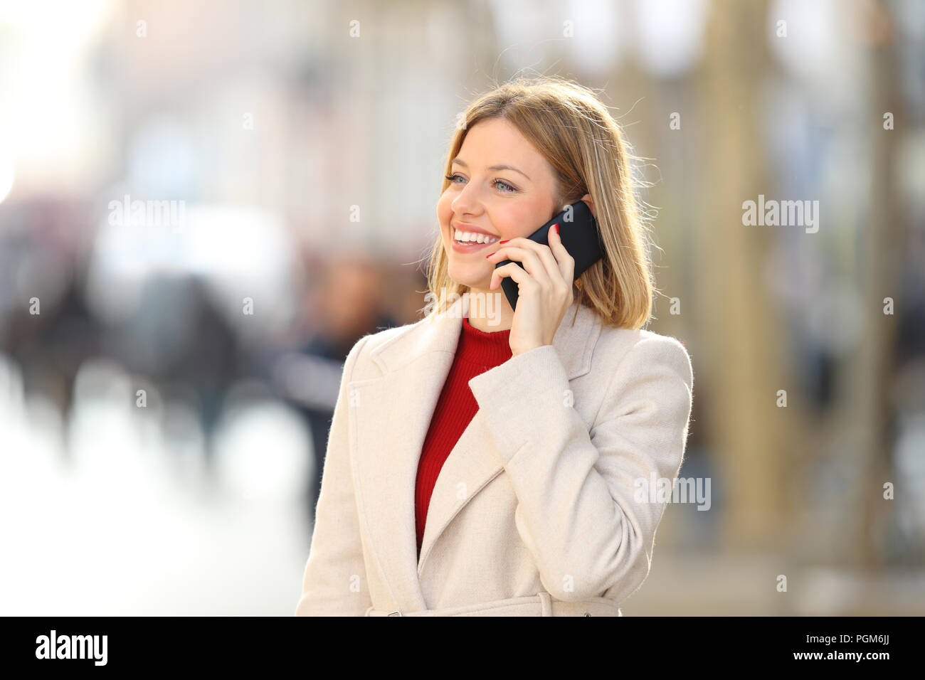 Happy woman having a phone parler debout en hiver dans la rue Banque D'Images