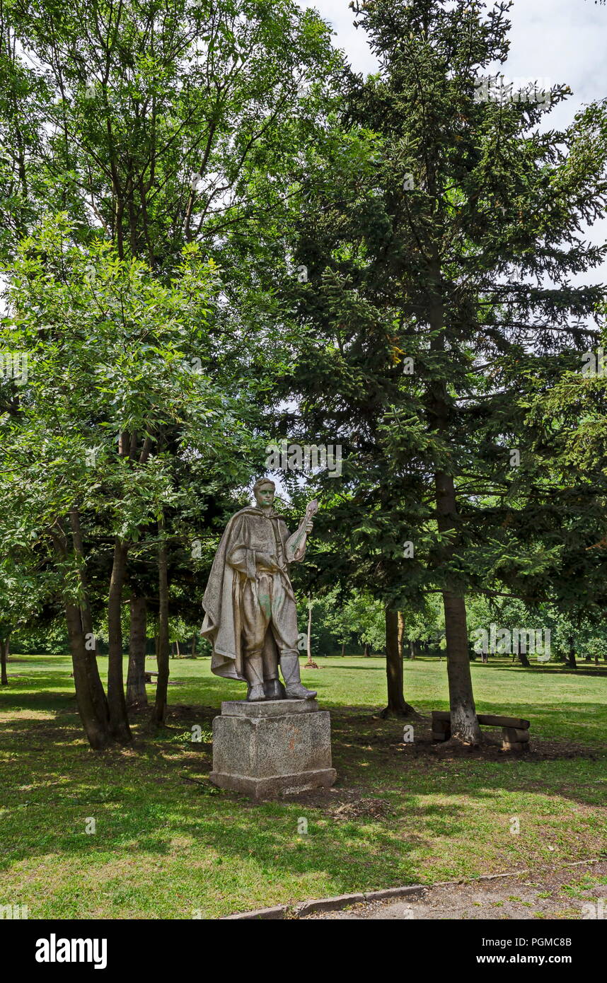 Paysage d'été la nature avec la forêt de feuillus et ancienne statue de jeune homme bulgare dans le Old West Park, Sofia, Bulgarie Banque D'Images