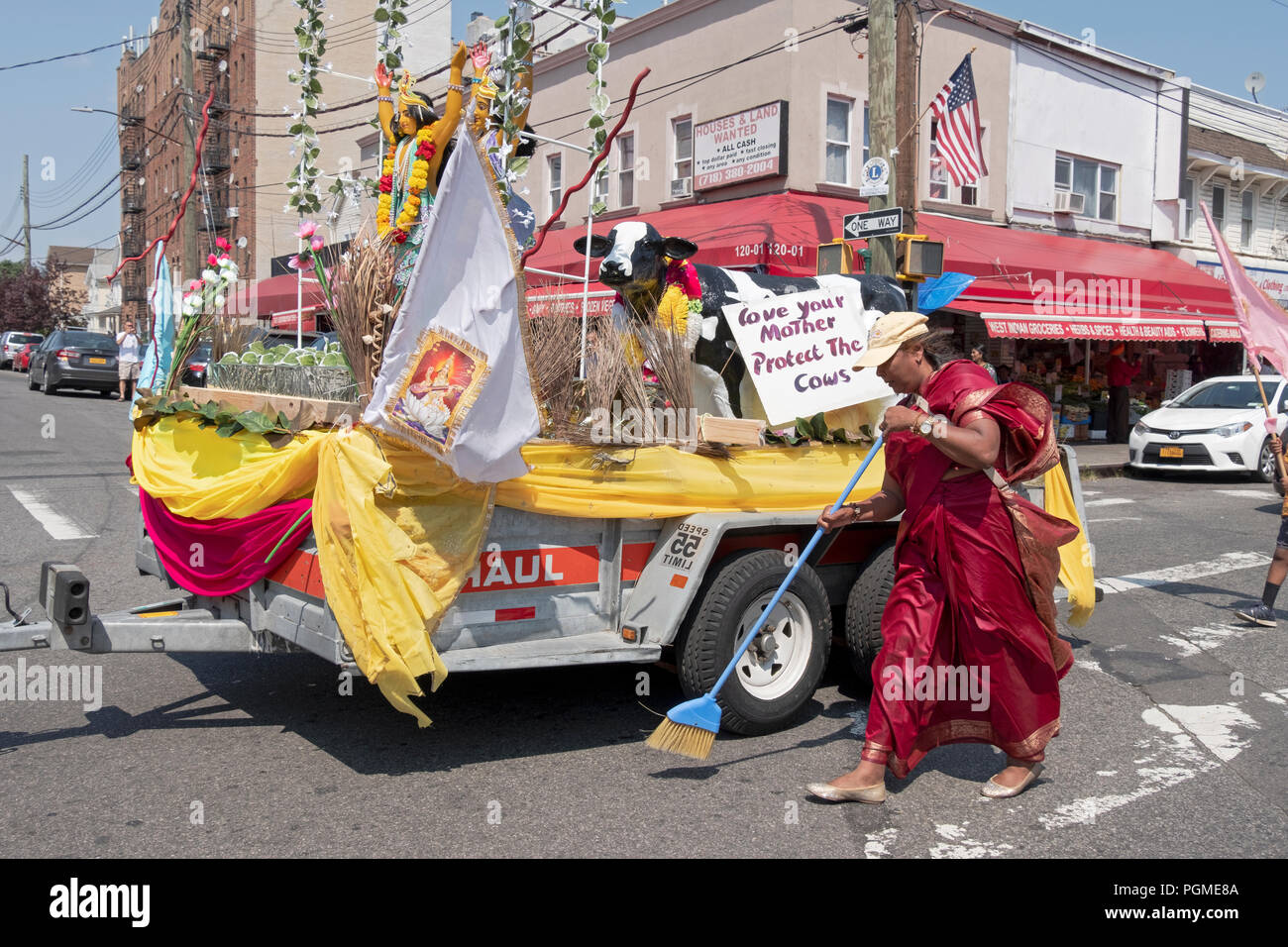 Comme un acte de dévotion, la femme hindoue balaie un chemin pour un flotteur avec des statues de divinités hindoues au Queens, New York Rathayatra Parade. Banque D'Images