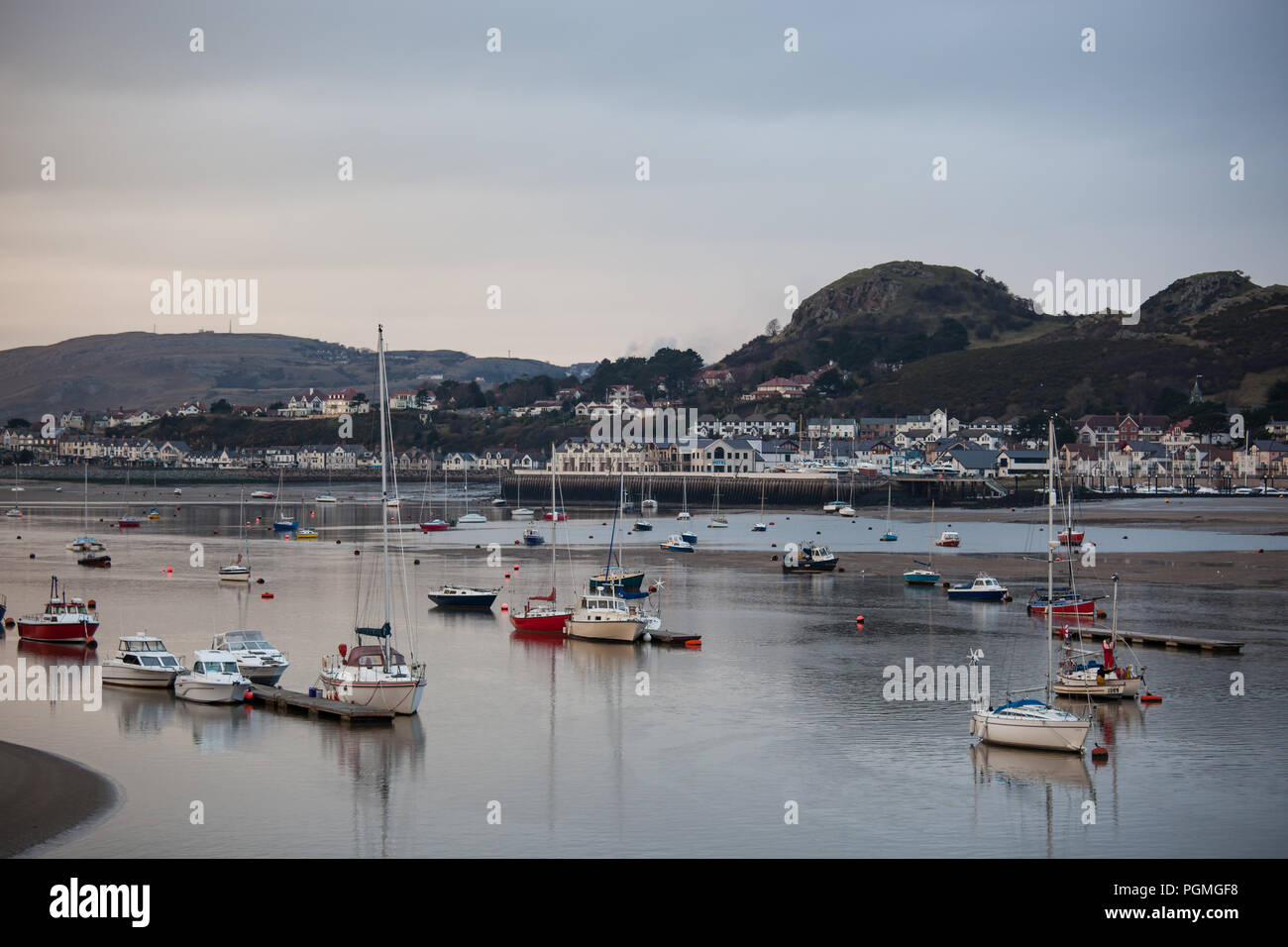 Bateaux amarrés dans le estauary Conway à marée basse comme coucher de soleil. Banque D'Images