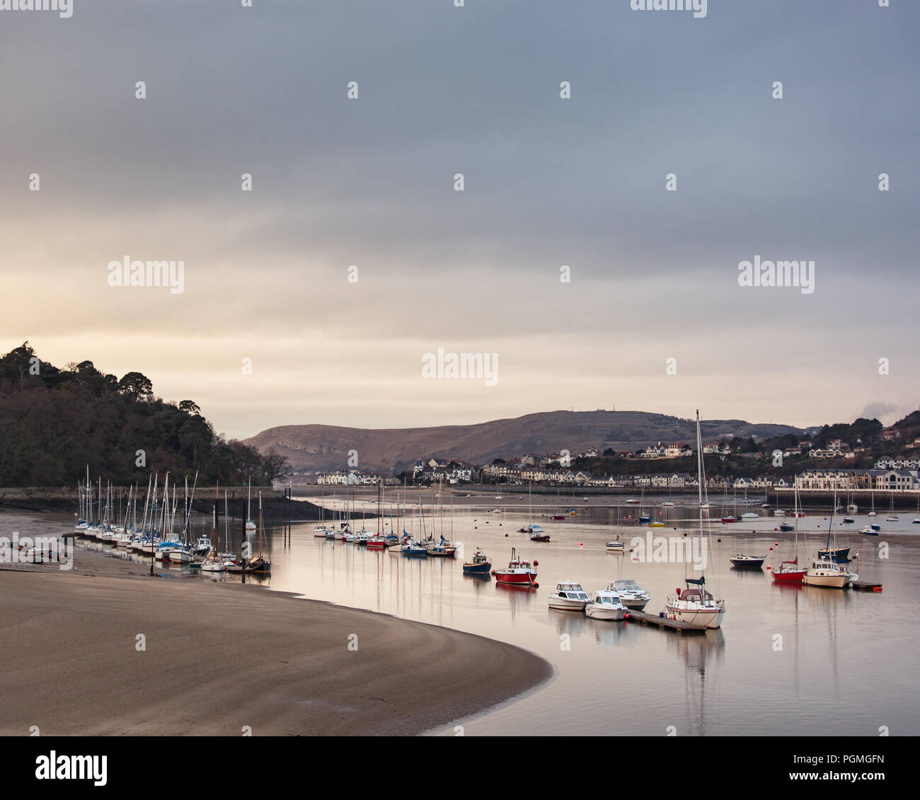 Bateaux amarrés dans le estauary Conway à marée basse comme coucher de soleil. Banque D'Images
