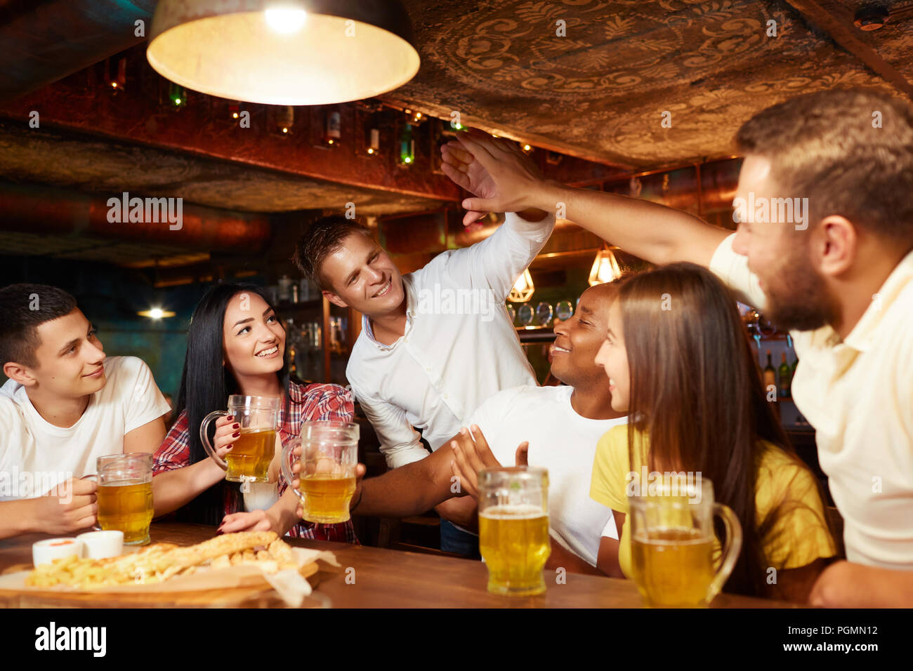 Société d'amis de langue et d'avoir de l'alcool au bar. L'un des hommes d'accueil uniquement au cours de la gars à table, offrant un rapport cinq l'un d'entre eux. Toutes les personnes Banque D'Images