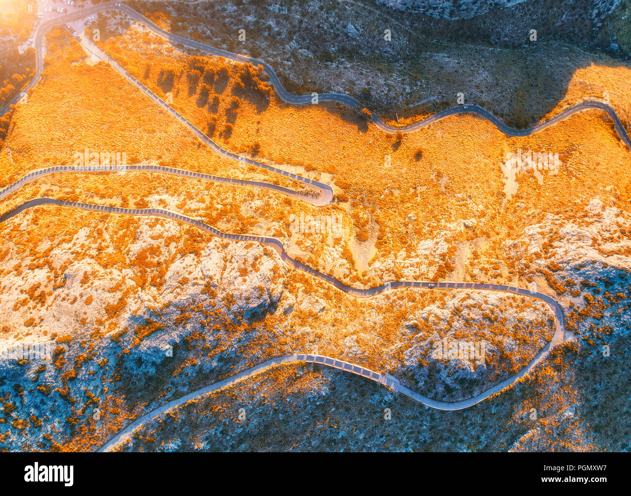 Vue aérienne de la courbe de la montagne avec des voitures de route, forêt d'orange au coucher du soleil en automne en Europe. Paysage avec la route d'asphalte, des arbres sur les rochers. L'autoroute e Banque D'Images