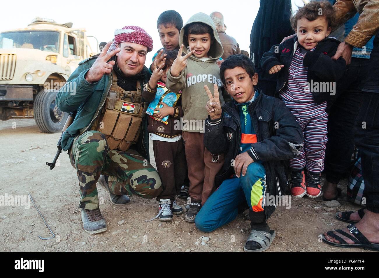 Un camp de réfugiés en Irak, où vivent les gens échappés d'ISIS. Un soldat kurde avec certains enfants. Banque D'Images