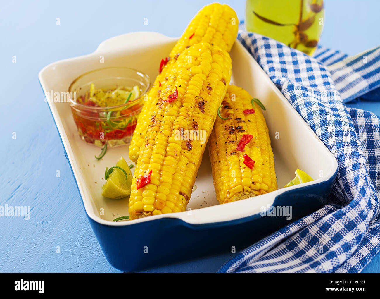 Maïs doux grillé avec sauce mexicaine, piment et citron vert sur fond bleu. L'alimentation d'été en bonne santé. Banque D'Images