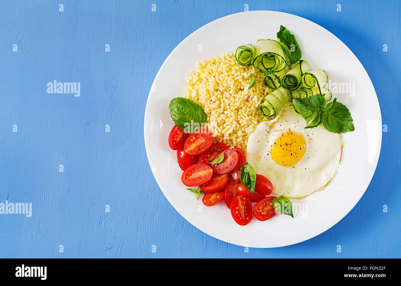 Petit déjeuner sain. Menu diététique. Porridge de millet et de tomates, salade de concombre et d'œufs au plat. Vue d'en haut. Mise à plat Banque D'Images