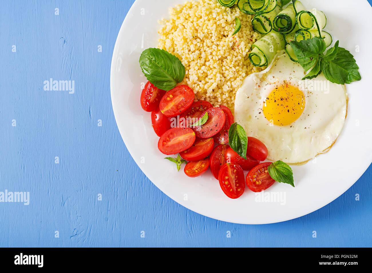 Petit déjeuner sain. Menu diététique. Porridge de millet et de tomates, salade de concombre et d'œufs au plat. Vue d'en haut. Mise à plat Banque D'Images