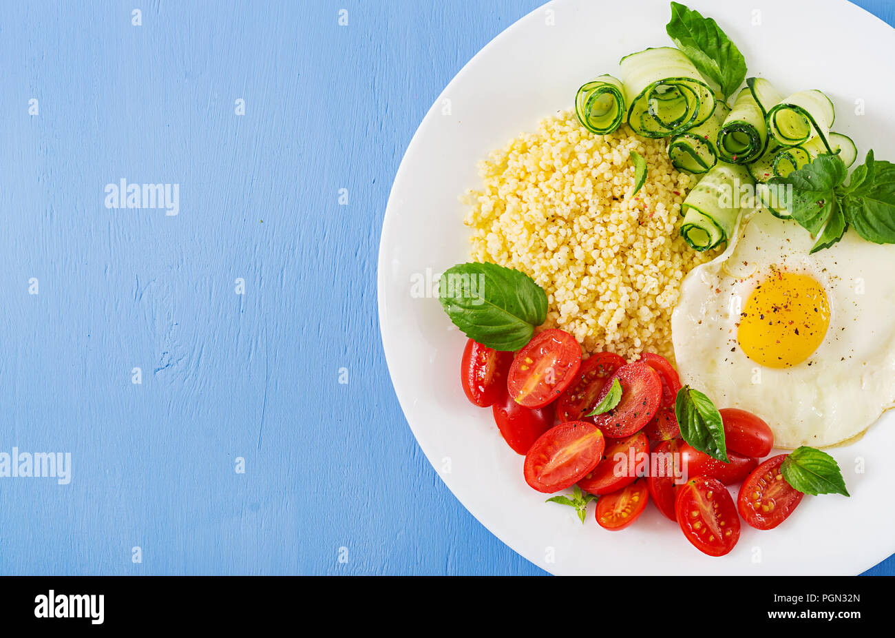 Petit déjeuner sain. Menu diététique. Porridge de millet et de tomates, salade de concombre et d'œufs au plat. Vue d'en haut. Mise à plat Banque D'Images