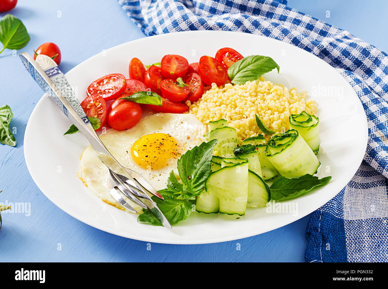Petit déjeuner sain. Menu diététique. Porridge de millet et de tomates, salade de concombre et d'œufs au plat. Banque D'Images