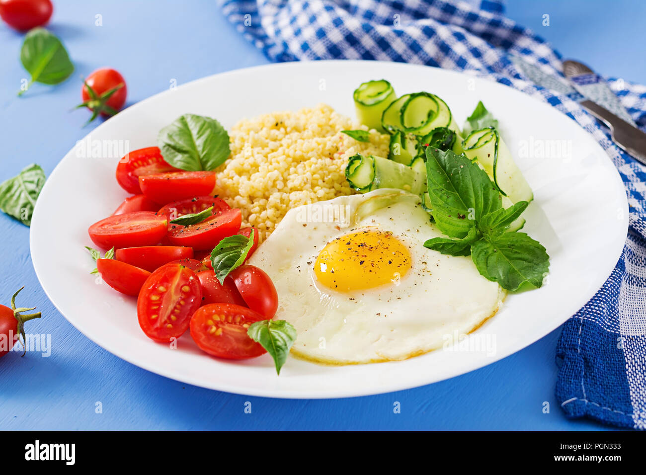 Petit déjeuner sain. Menu diététique. Porridge de millet et de tomates, salade de concombre et d'œufs au plat. Banque D'Images