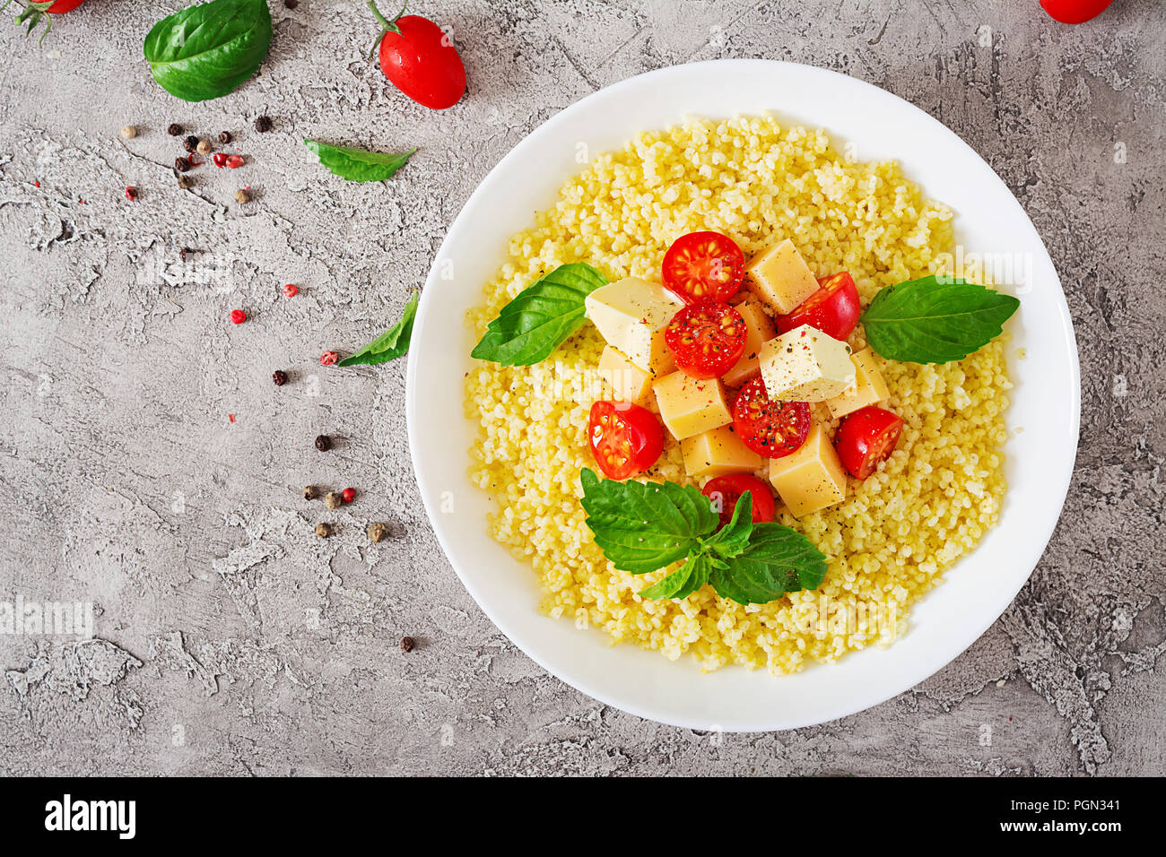 Bouillie de mil avec le fromage, le beurre et le basilic dans un bol blanc. La nourriture bonne. Le petit-déjeuner. Vue d'en haut. Mise à plat Banque D'Images