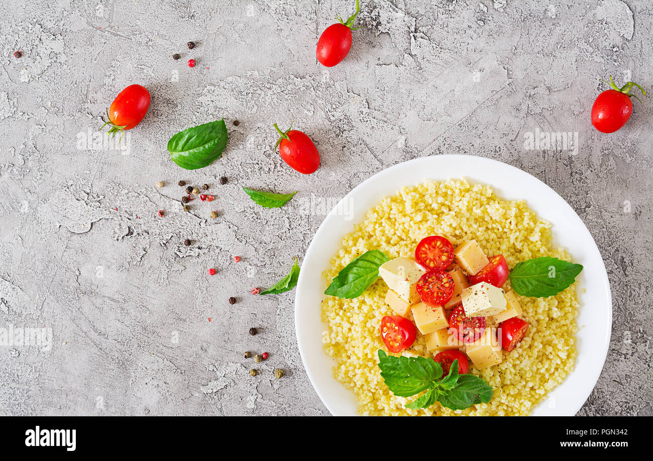 Bouillie de mil avec le fromage, le beurre et le basilic dans un bol blanc. La nourriture bonne. Le petit-déjeuner. Vue d'en haut. Mise à plat Banque D'Images