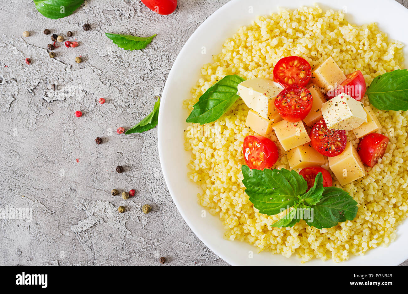 Bouillie de mil avec le fromage, le beurre et le basilic dans un bol blanc. La nourriture bonne. Le petit-déjeuner. Vue d'en haut. Mise à plat Banque D'Images