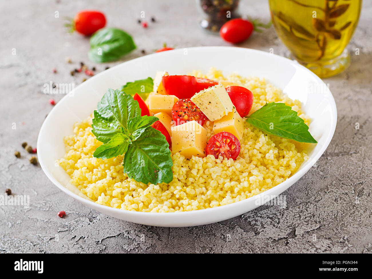 Bouillie de mil avec le fromage, le beurre et le basilic dans un bol blanc. La nourriture bonne. Le petit-déjeuner. Banque D'Images
