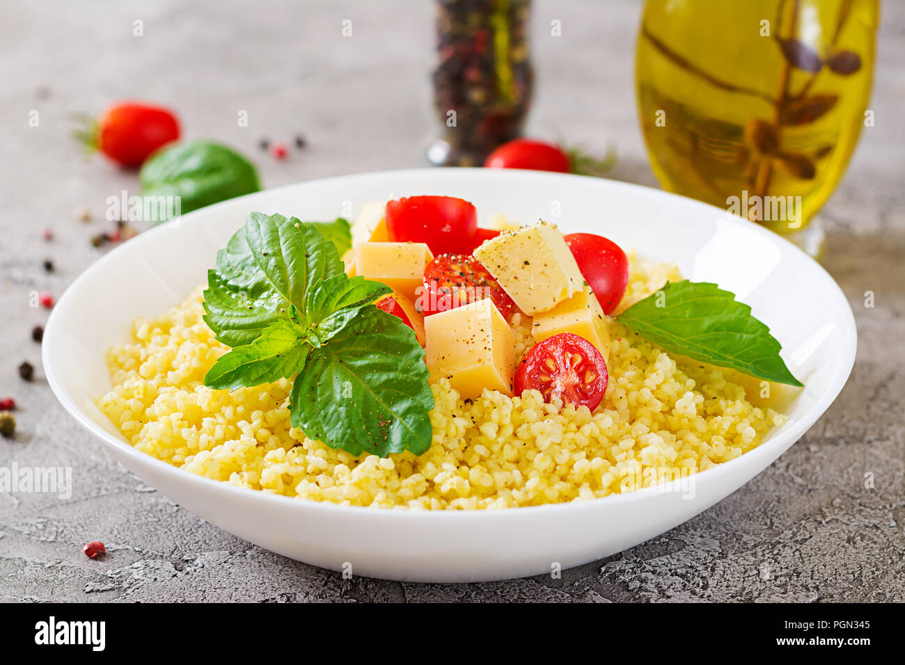 Bouillie de mil avec le fromage, le beurre et le basilic dans un bol blanc. La nourriture bonne. Le petit-déjeuner. Banque D'Images