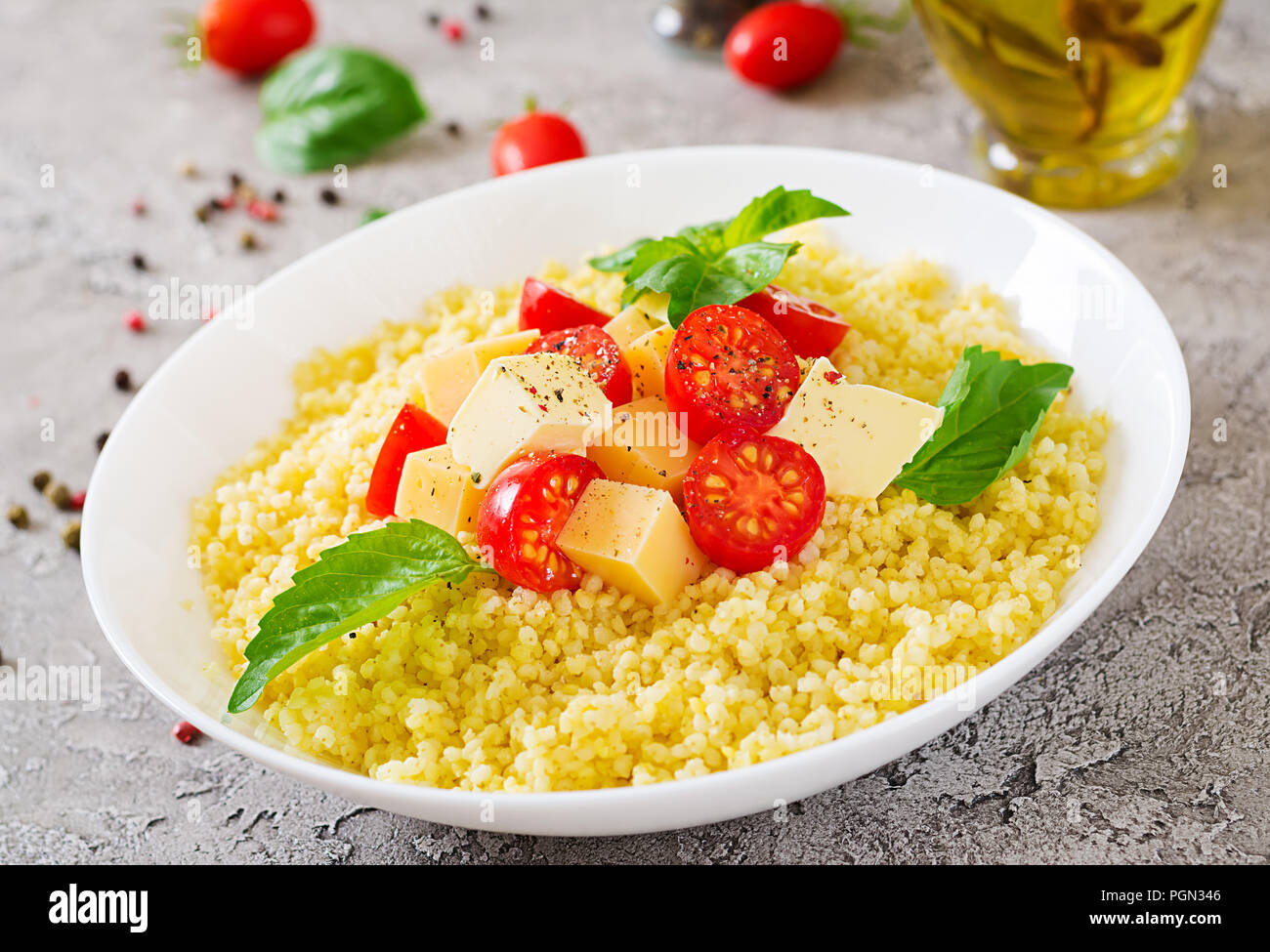 Bouillie de mil avec le fromage, le beurre et le basilic dans un bol blanc. La nourriture bonne. Le petit-déjeuner. Banque D'Images