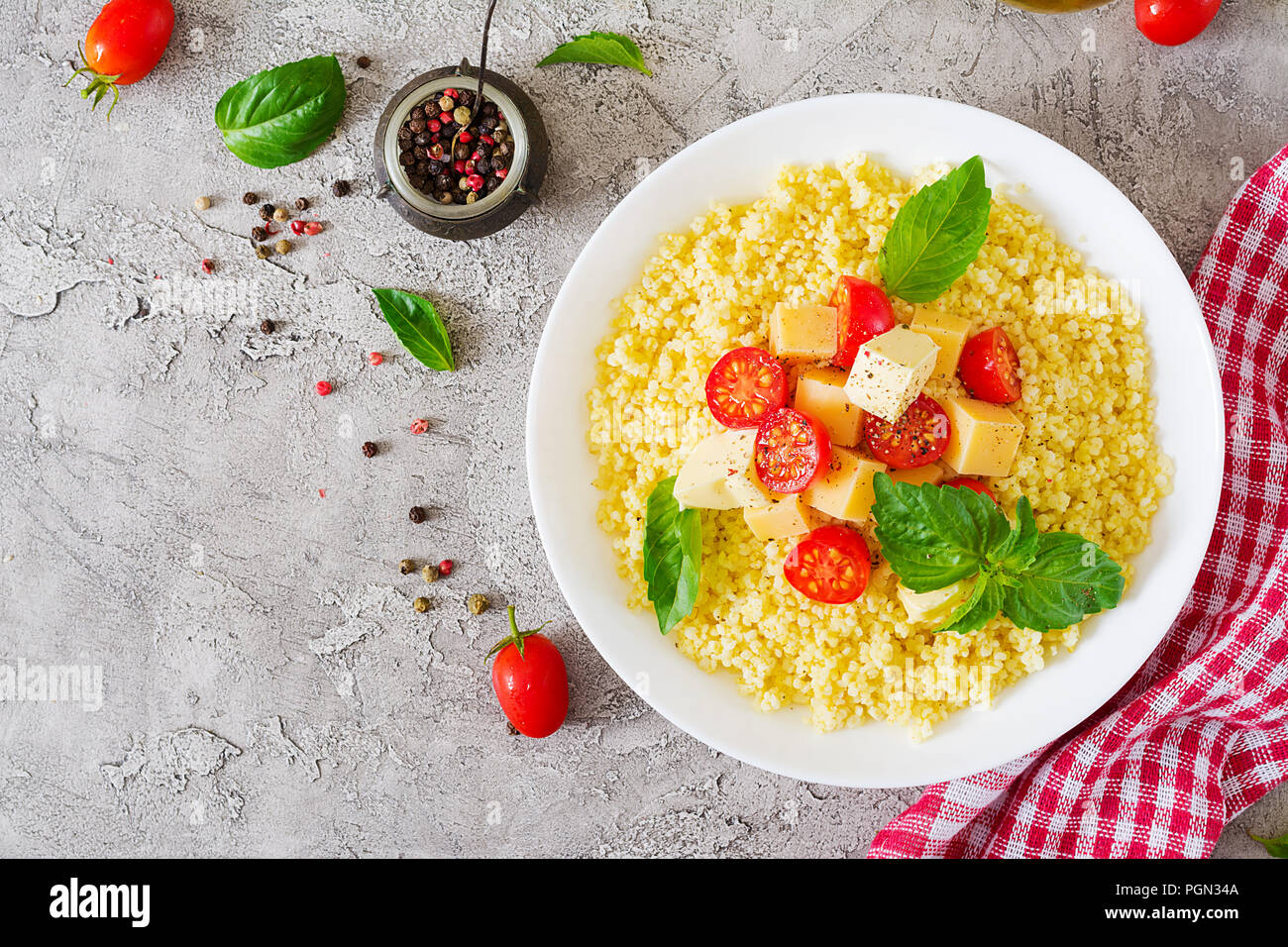 Bouillie de mil avec le fromage, le beurre et le basilic dans un bol blanc. La nourriture bonne. Le petit-déjeuner. Vue d'en haut. Mise à plat Banque D'Images