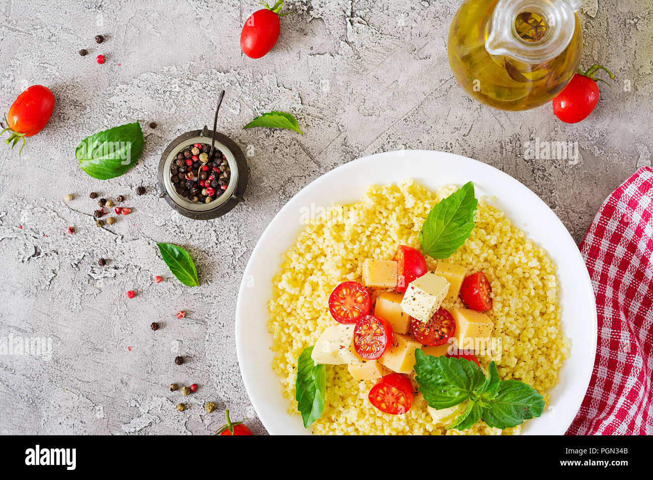 Bouillie de mil avec le fromage, le beurre et le basilic dans un bol blanc. La nourriture bonne. Le petit-déjeuner. Vue d'en haut. Mise à plat Banque D'Images