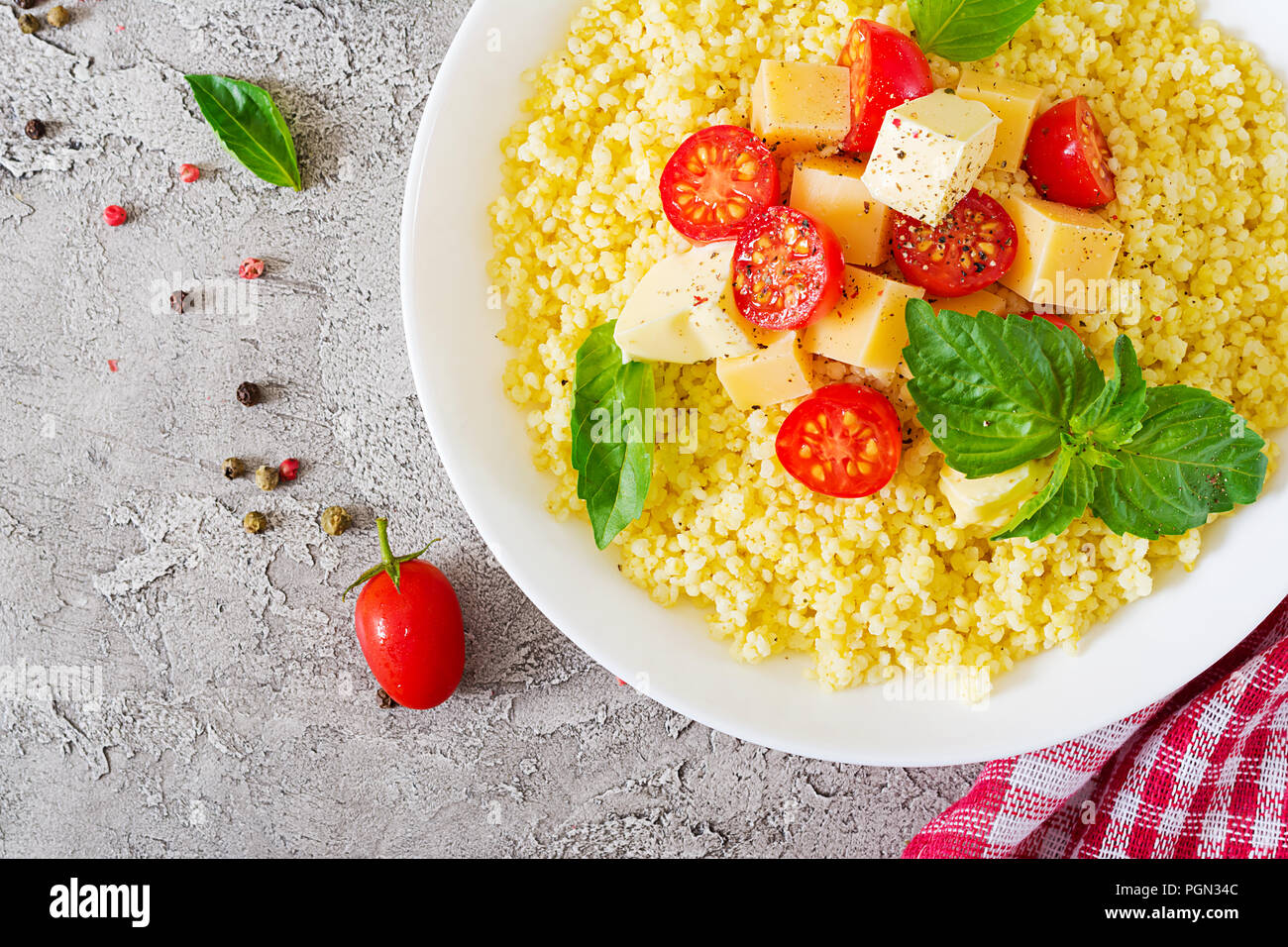 Bouillie de mil avec le fromage, le beurre et le basilic dans un bol blanc. La nourriture bonne. Le petit-déjeuner. Vue d'en haut. Mise à plat Banque D'Images