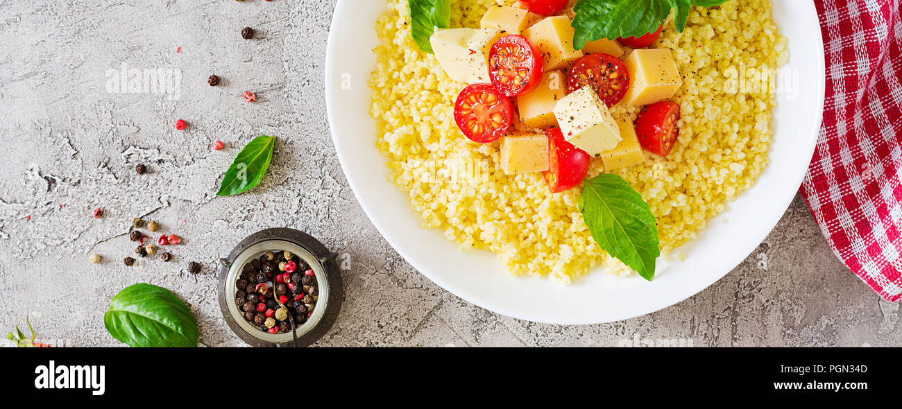 Bouillie de mil avec le fromage, le beurre et le basilic dans un bol blanc. La nourriture bonne. Le petit-déjeuner. Bannière. Vue d'en haut. Mise à plat Banque D'Images