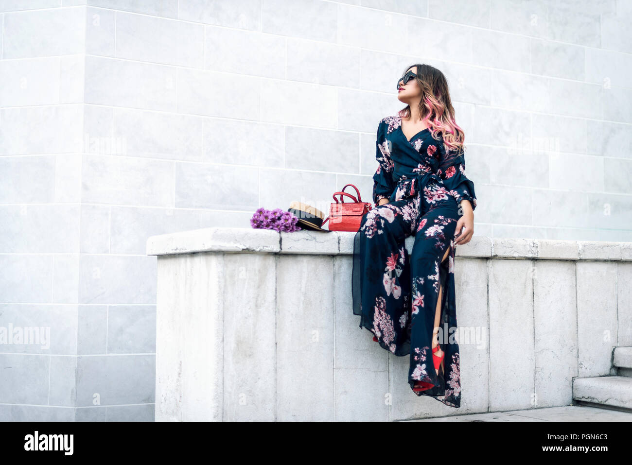 Belle femme sensuelle fashion avec fleurs et hat posing sur mur de pierre blanche. La tonalité de l'image. Banque D'Images
